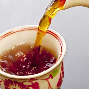 peach oolong tea being poured into a ceramic cup