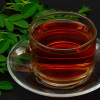 cup of strawberry moringa tea with moringa leaves